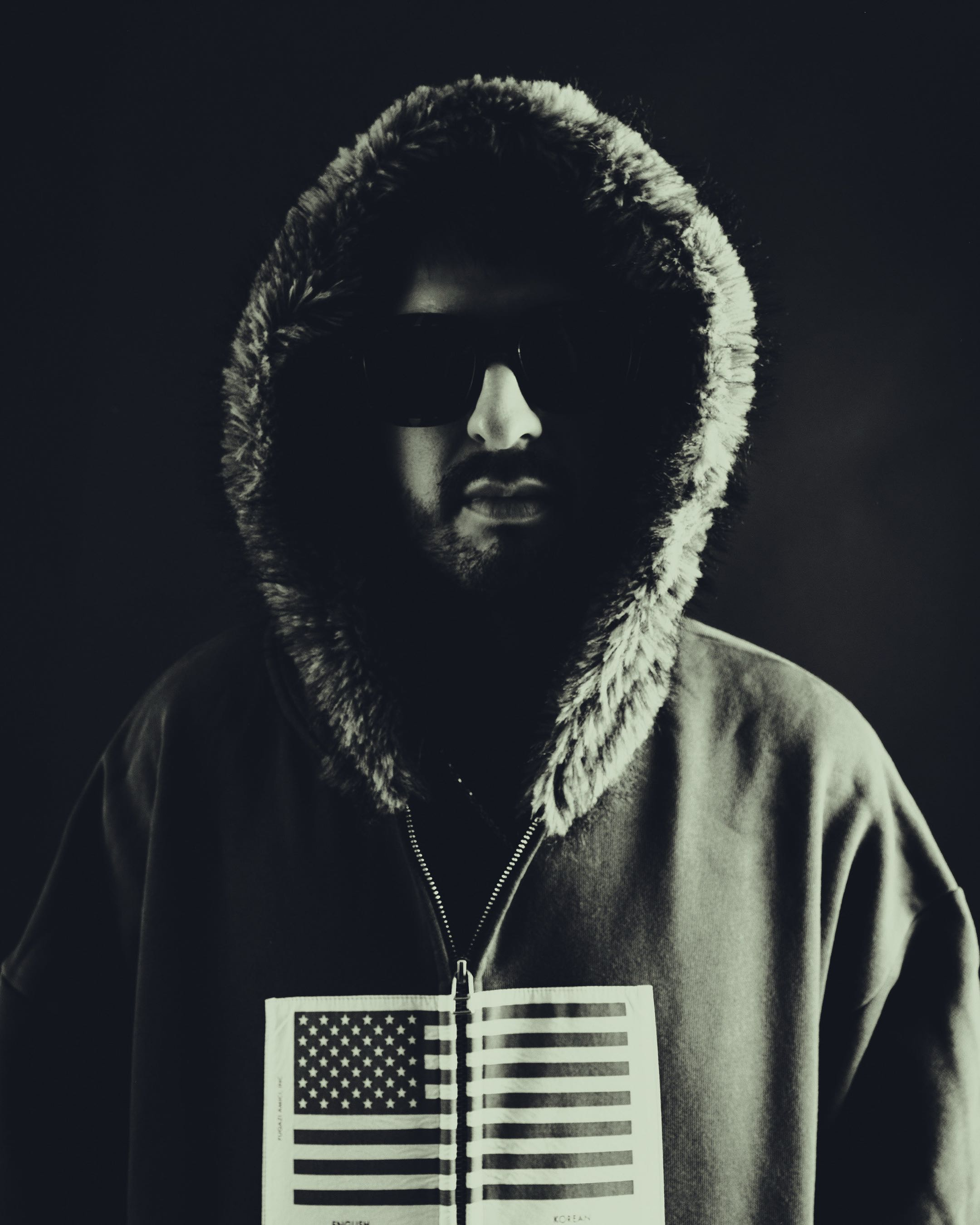 Portrait of Chris Miglioranzi wearing a fur-lined hood and sunglasses